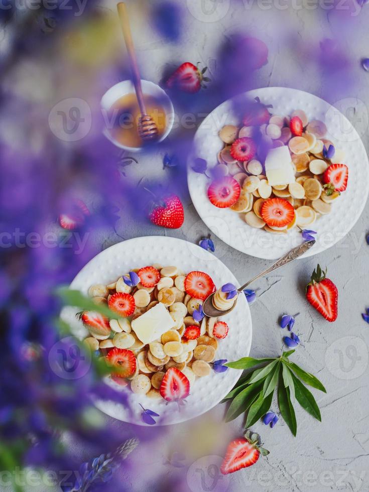 crêpes aux céréales, nourriture à la mode. mini crêpes aux céréales avec du beurre, du miel et des fraises. photo