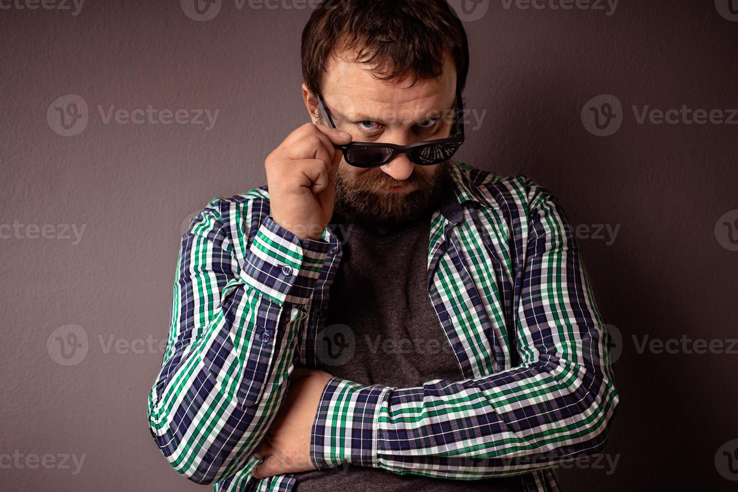 bel homme barbu hipster avec des lunettes de soleil et une chemise tenant ses lunettes de soleil photo