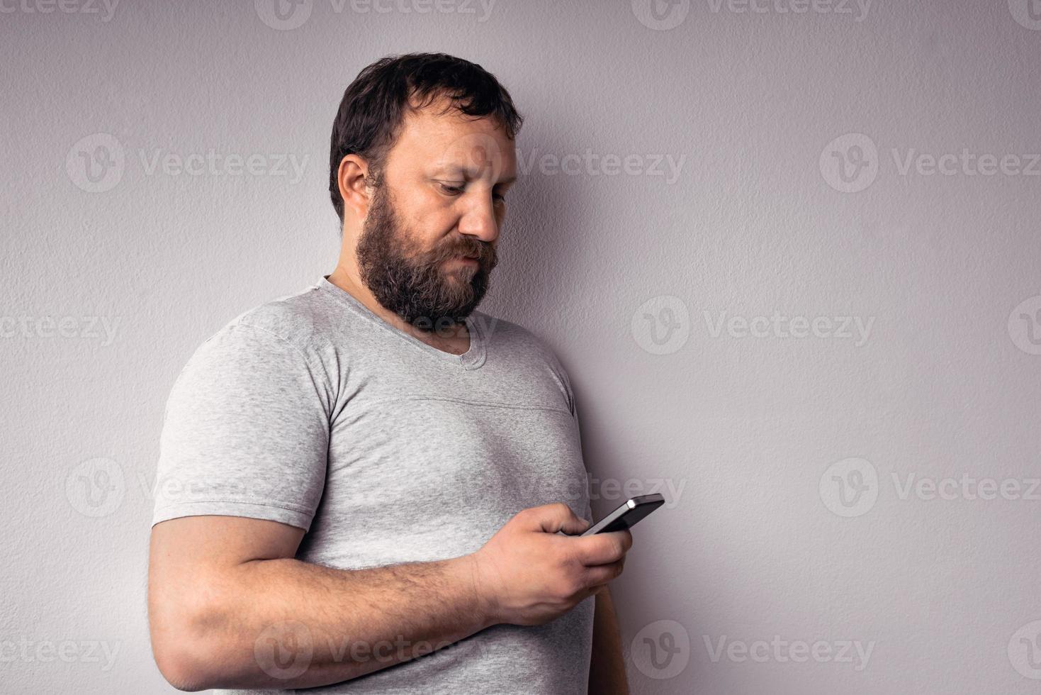 homme barbu en t-shirt gris tenant un téléphone portable photo
