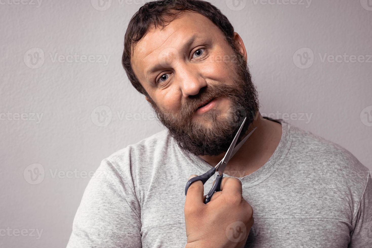 bel homme barbu en t-shirt gris coupant sa barbe photo