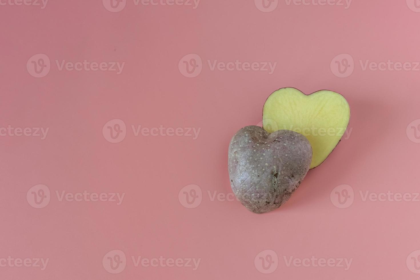 pommes de terre en forme de coeur coupées en deux sur fond rose. concept d'agriculture, de récolte, de végétarisme photo