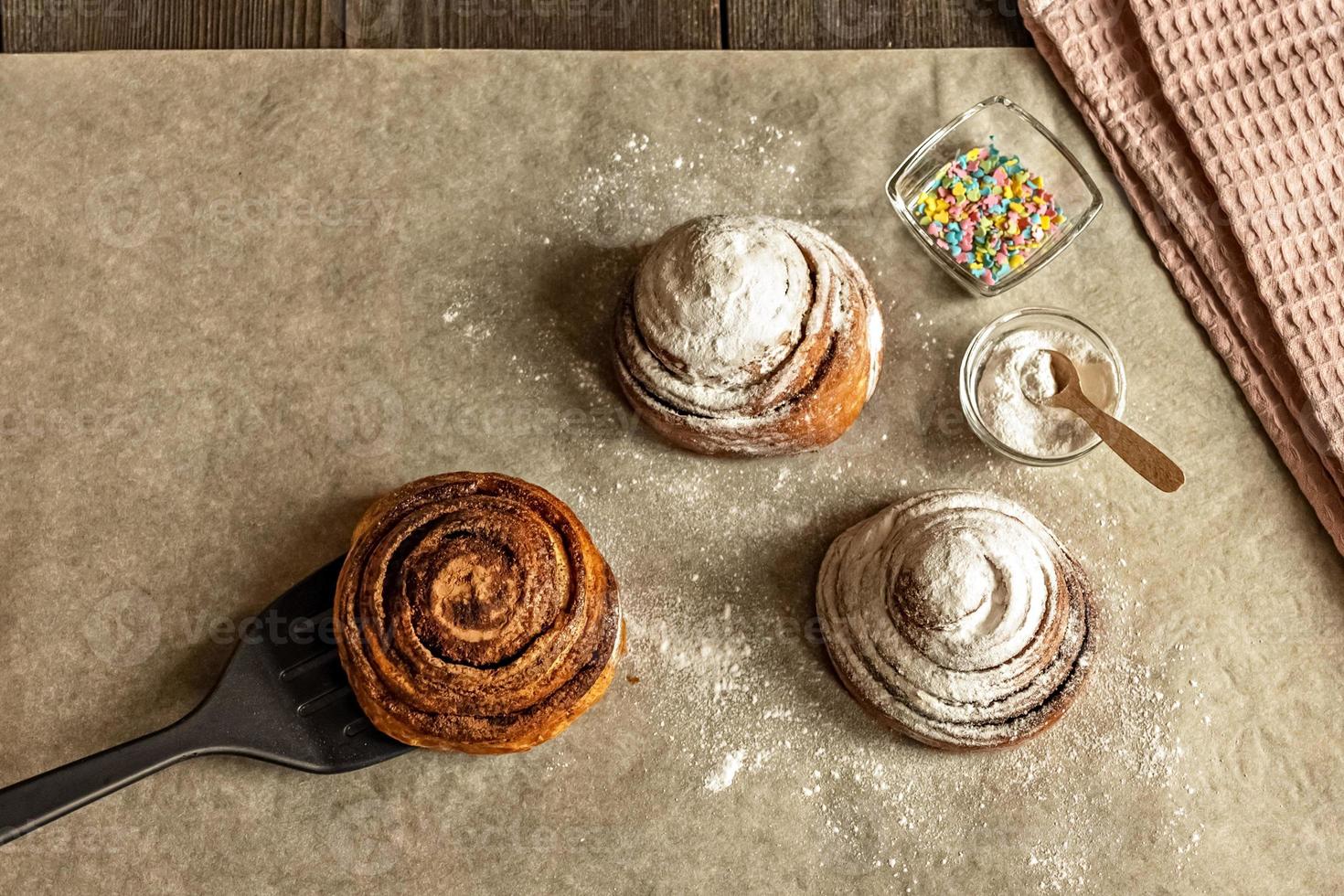 petits pains à la cannelle fraîchement cuits, saupoudrés de sucre en poudre et de garniture de pâtisserie photo