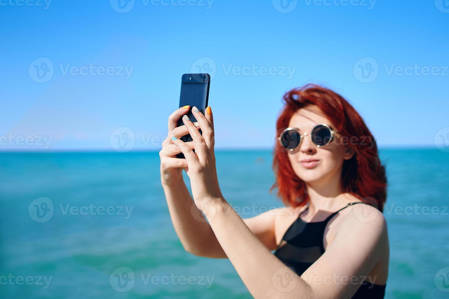 femme rousse prend selfie sur l'appareil photo du smartphone.