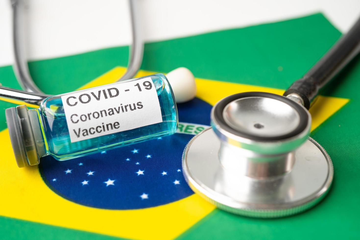 stéthoscope avec vaccin contre le coronavirus covid-19 sur le drapeau du brésil. photo