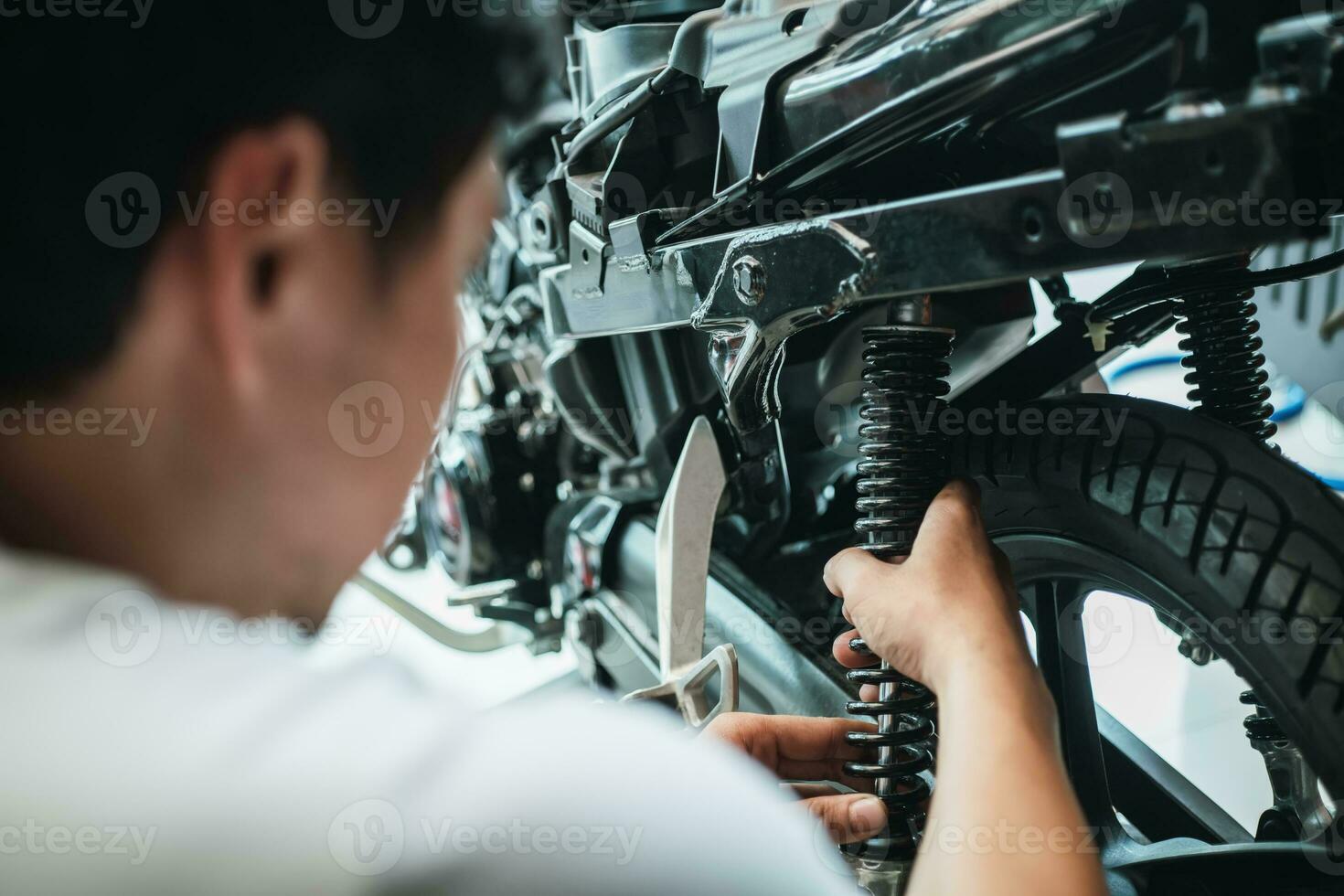 mécanicien de moto vérifier et changer les amortisseurs arrière scooter de moto au garage, réparation, entretien et concept de service de moto photo