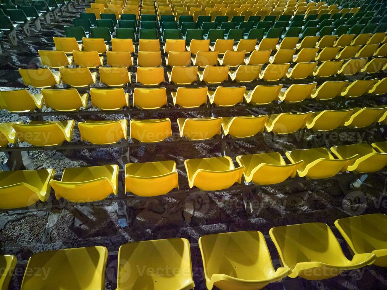 chaises en plastique rouges vides dans les gradins du stade ou de l'amphithéâtre. de nombreux sièges vides pour les spectateurs dans les gradins. photo