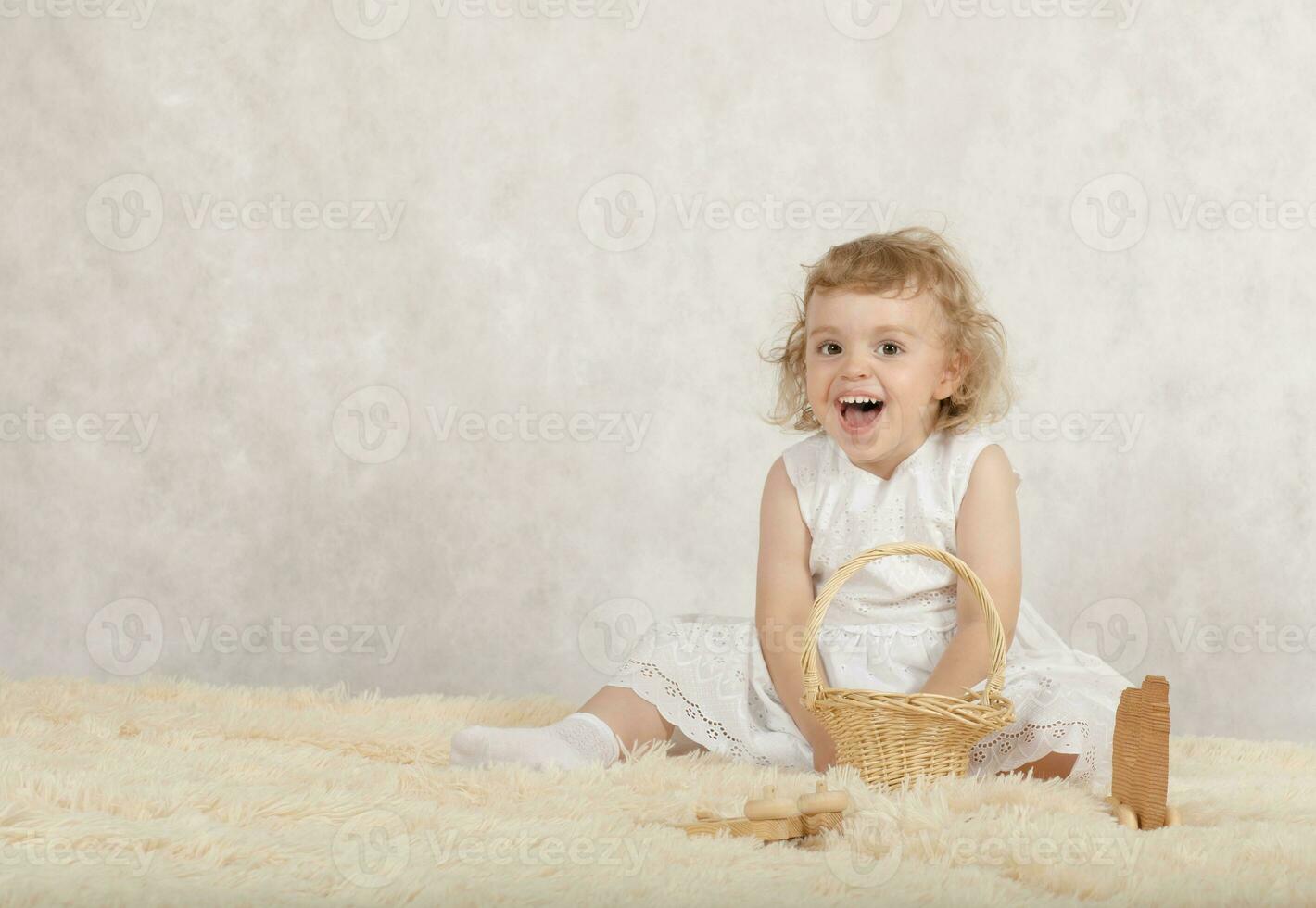 petit fille dans une blanc robe est en jouant avec sa jouets. photo