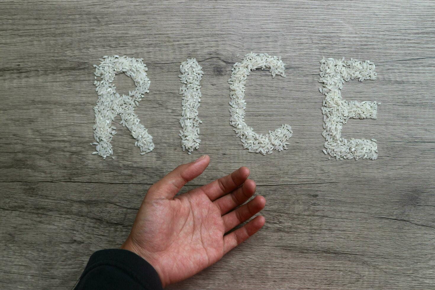 ouvert main demander geste, riz céréales forme le lettre riz sur une en bois Contexte. faim concept photo