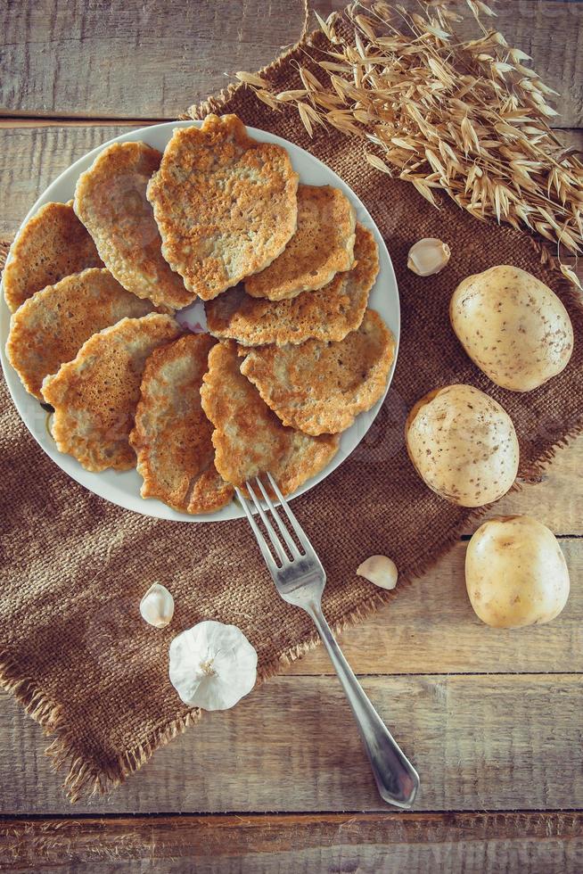 Crêpes de pommes de terre sur une assiette et une fourchette sur fond de lin photo