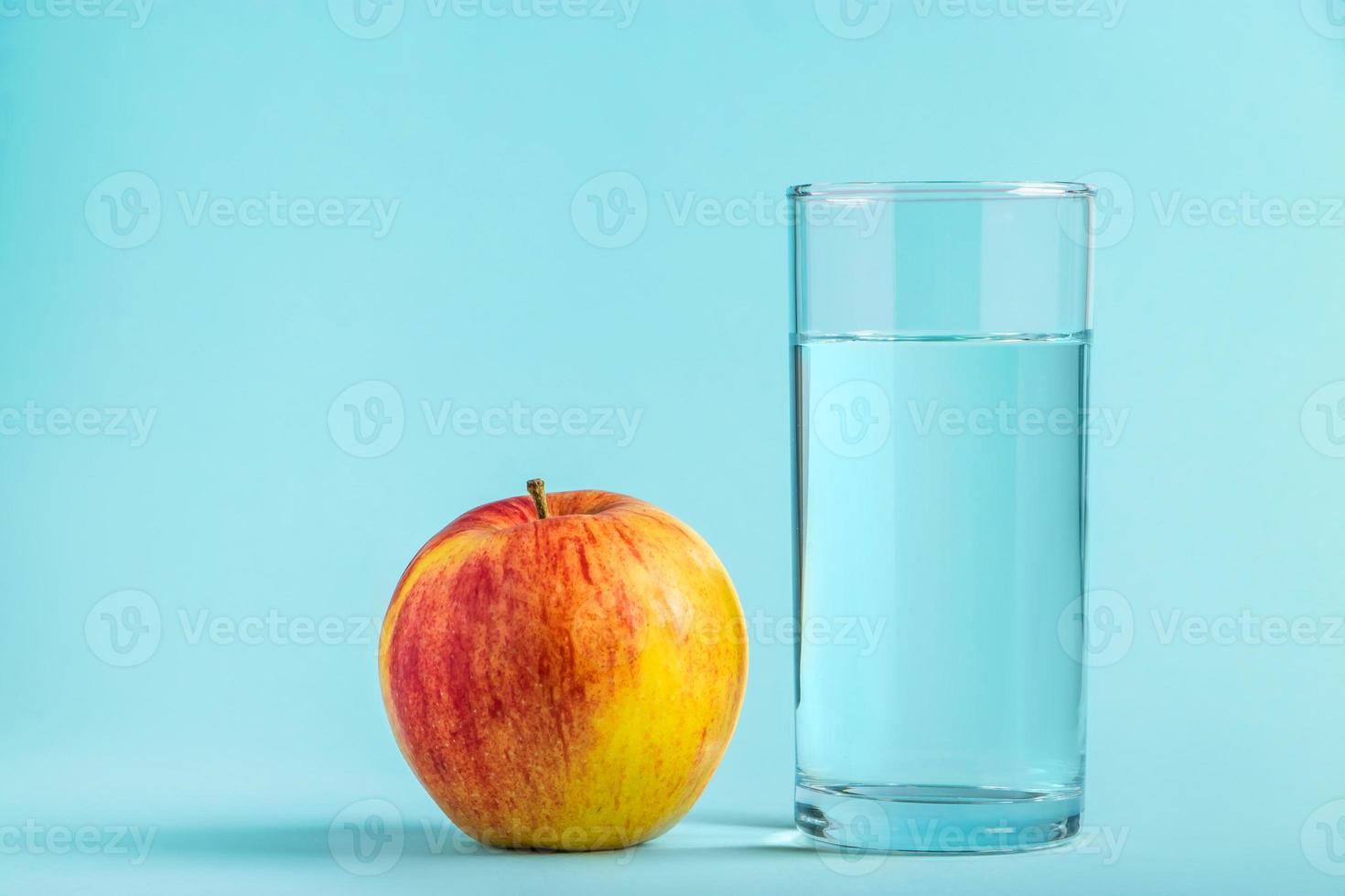 pomme et verre d'eau pure sur fond bleu. concept d'alimentation santé et diététique photo