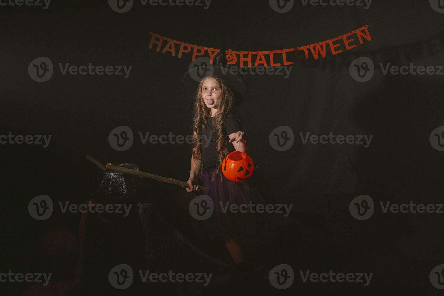 peu fille avec marrant rusé visage faire semblant comme en volant sur le balai sur Halloween vacances. enfant fille porter sorcière costume. fantaisie, Fée conte et mascarade concept. photo