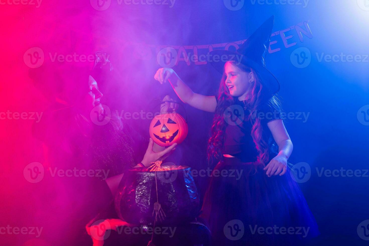 marrant enfant fille et femme dans sorcières costumes pour Halloween avec citrouille jack. photo