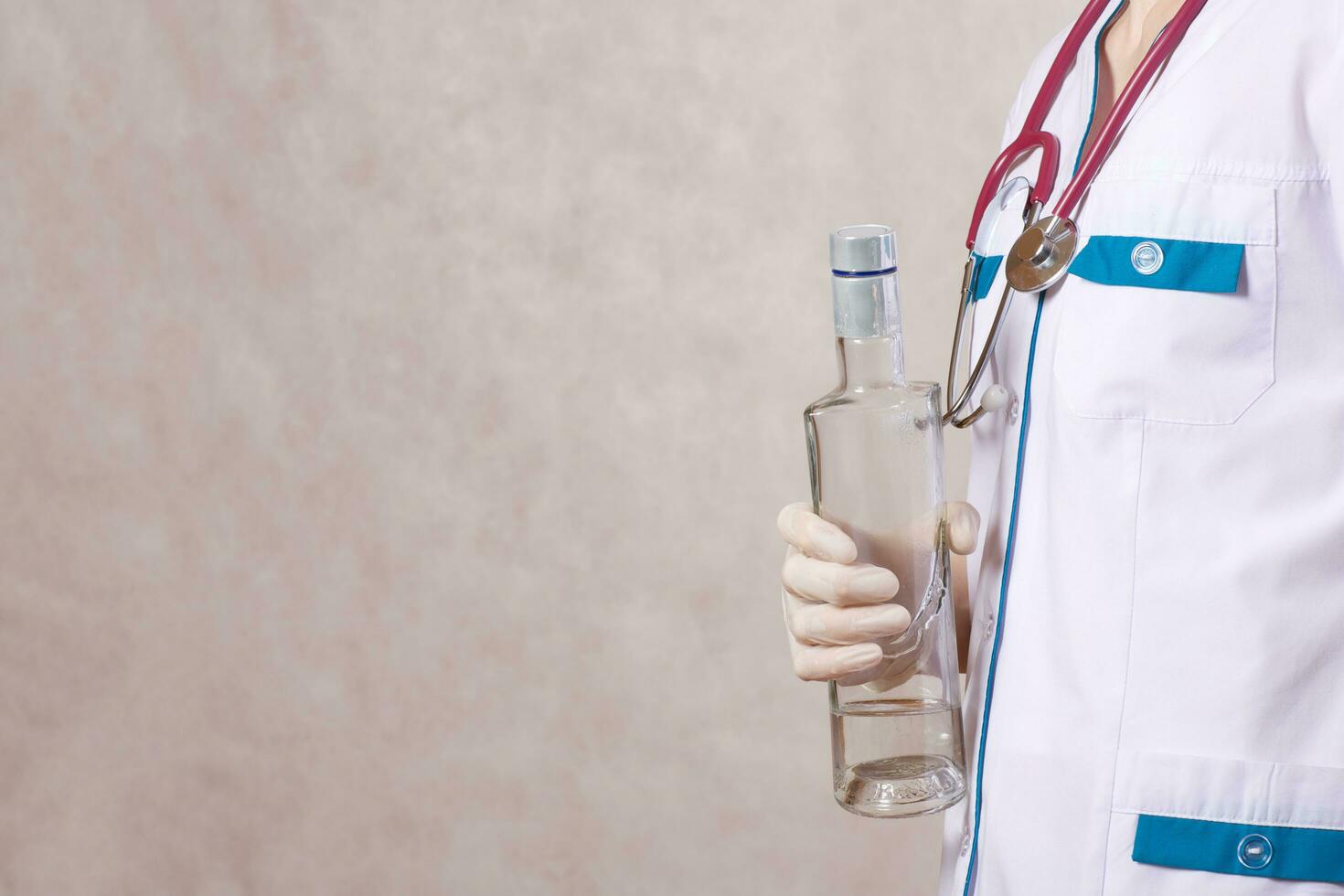 une Jeune femme habillé dans une médical uniforme garde une bouteille de alcool. fermer photo