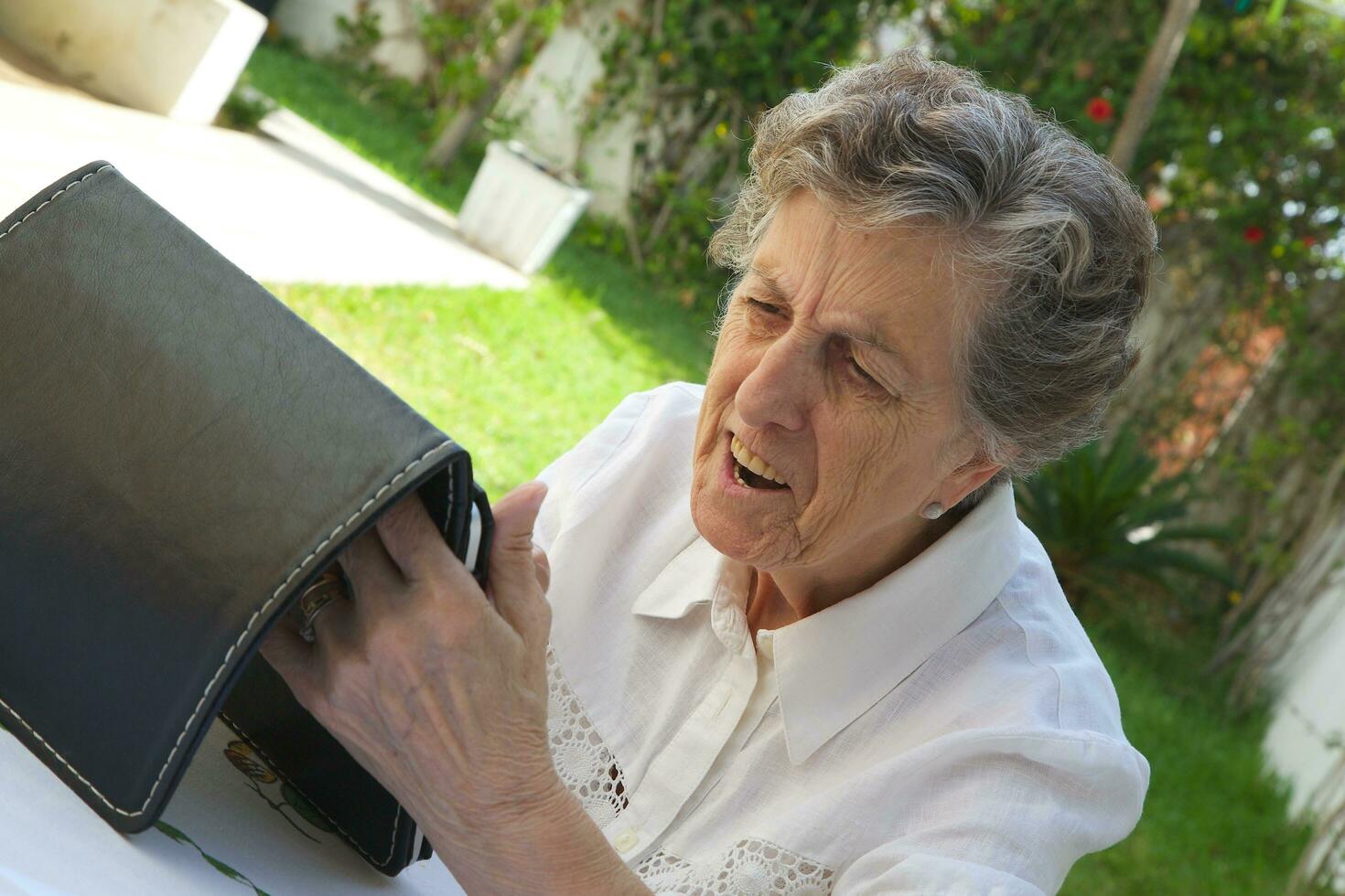 un vieux femme est en train de regarder une tablette photo