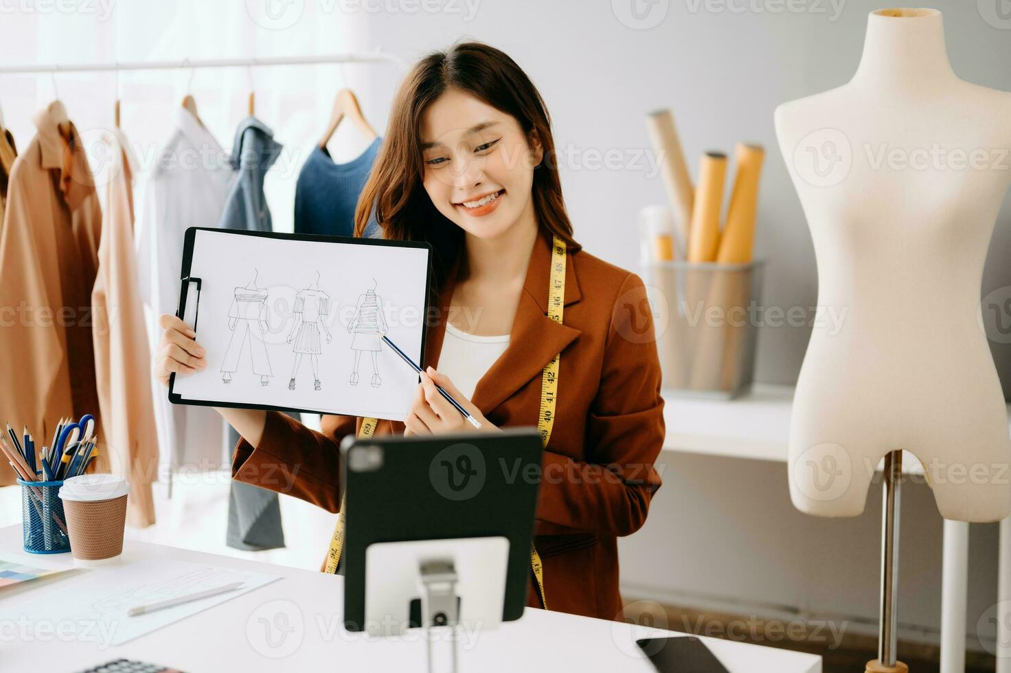 asiatique tailleur femme travail sur vêtements dans adaptation atelier. magnifique Jeune femelle mode designer sourire et après Succès dans studio photo