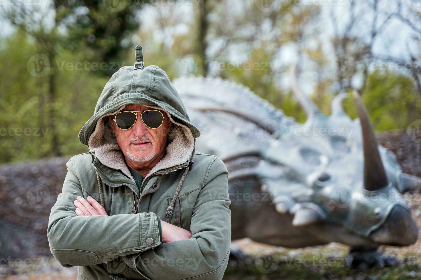 portrait de expressif milieu vieilli homme posant dans de face de dinosaure des modèles dans une parc photo