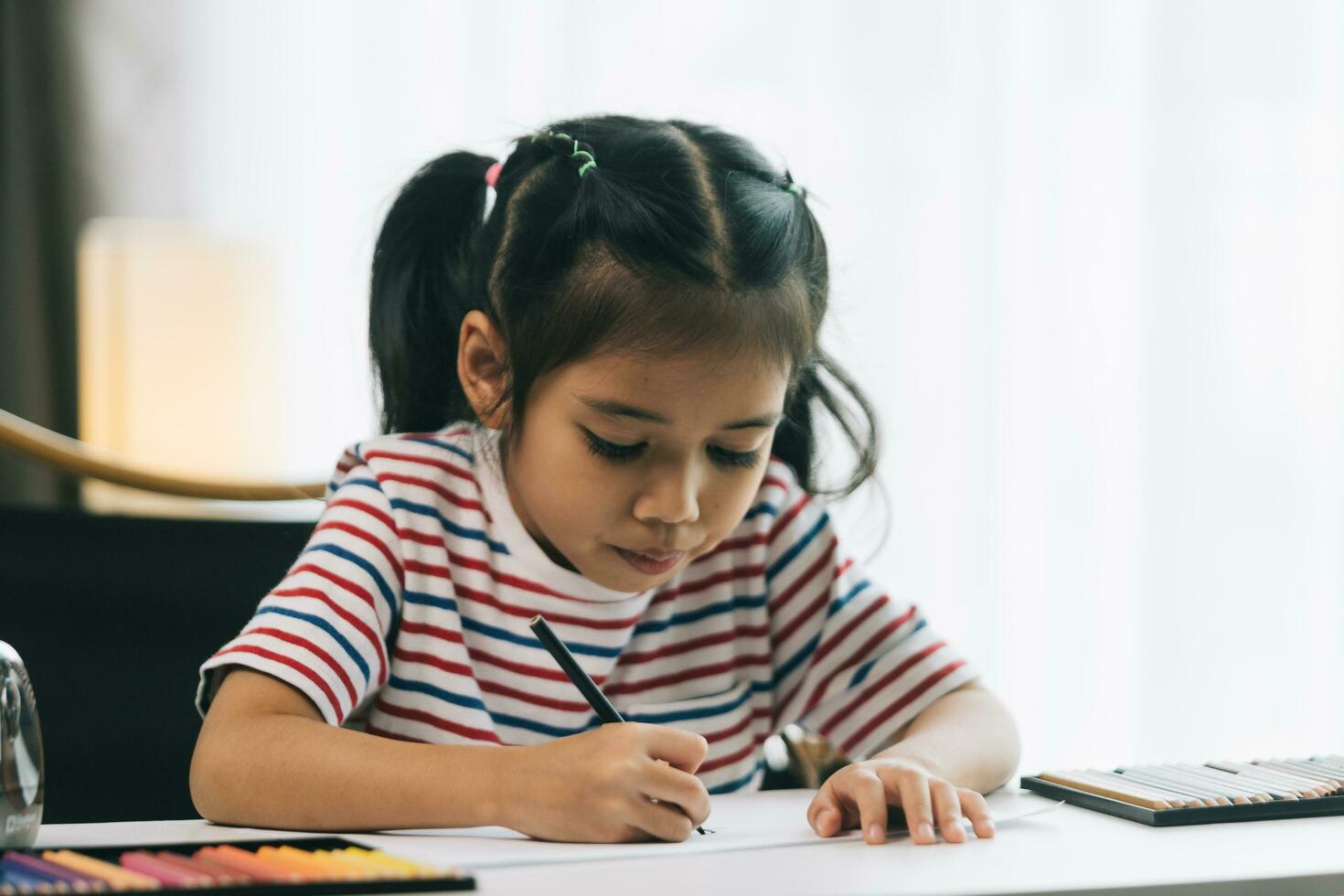 mignonne asiatique enfant fille dessin avec des crayons à maison. photo