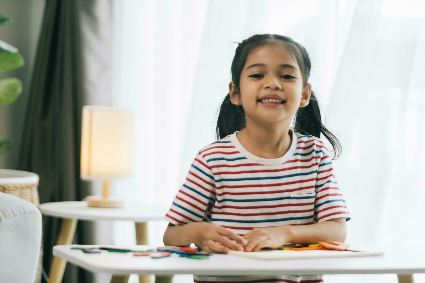 content asiatique enfant fille dessin avec coloré des crayons dans vivant pièce à Accueil photo