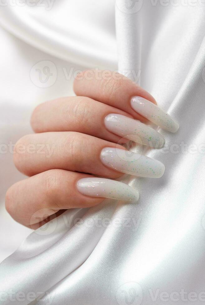 une femme mains avec une manucure sur eux, le ongles sont peint dans une blanc couleur. photo