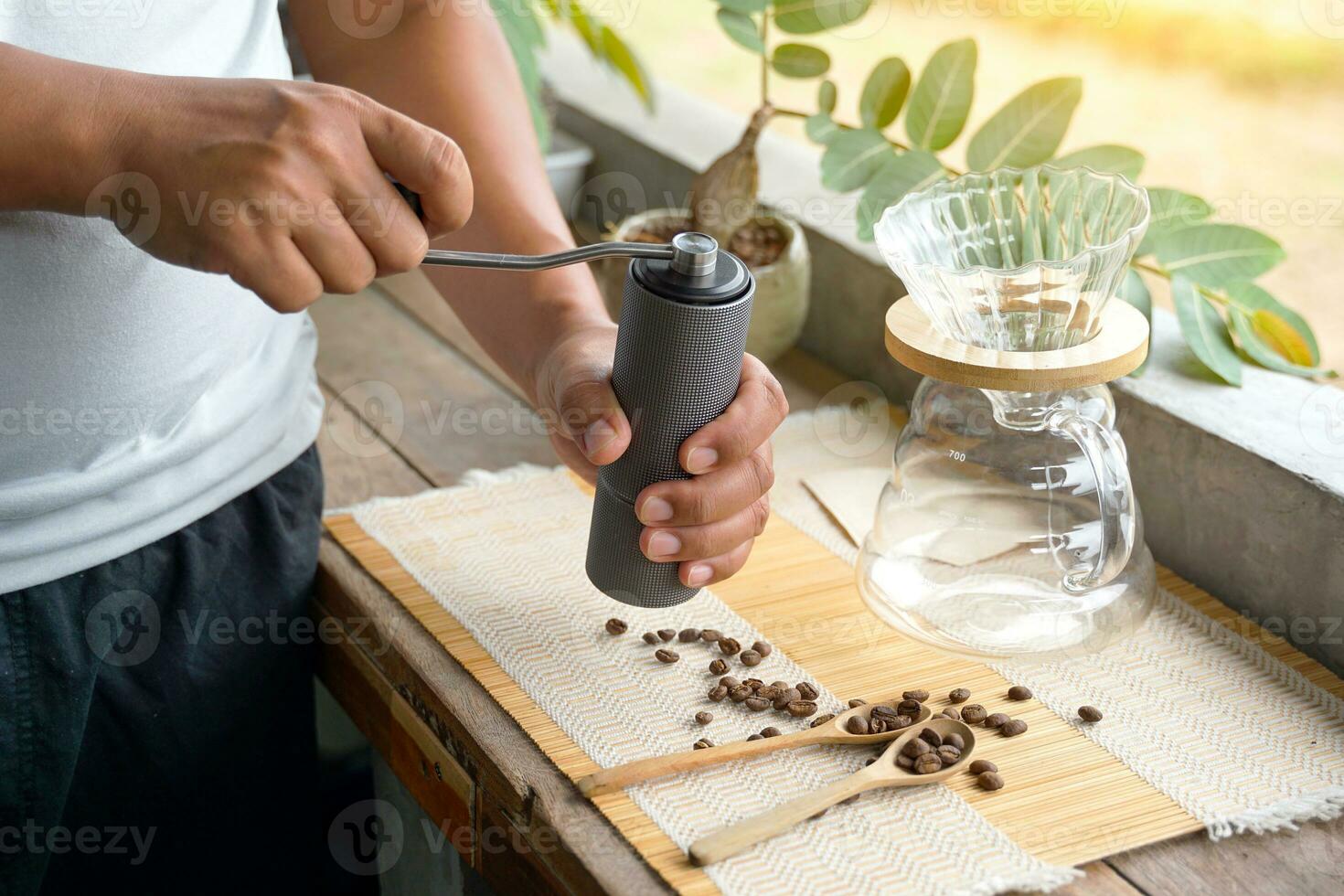 asiatique homme broyage café des haricots avec broyeur à facilement goutte noir café à maison, économie temps et avoir café cette a une spécial arôme et goût. doux et sélectif se concentrer. photo