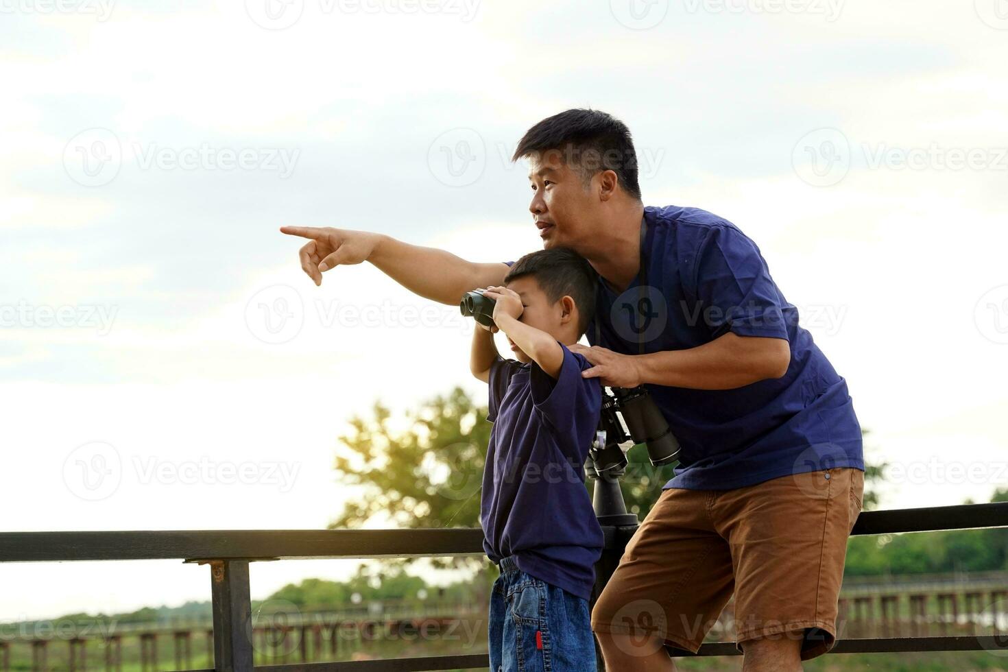 une père et fils utilisation jumelles à explorer le nature, des oiseaux et animaux autour le nationale parc tandis que camping avec le famille. le concept de Extérieur activités, la nature éducation, explorant la nature. photo