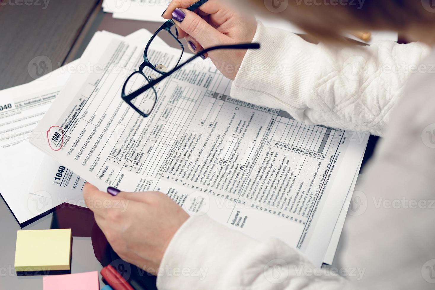 la femme remplit le formulaire fiscal, travaille avec des documents fiscaux. formulaire 1040 formulaire de déclaration de revenus des particuliers. formulaires fiscaux des États-Unis. formulaires fiscaux vierges américains. le temps des impôts. photo