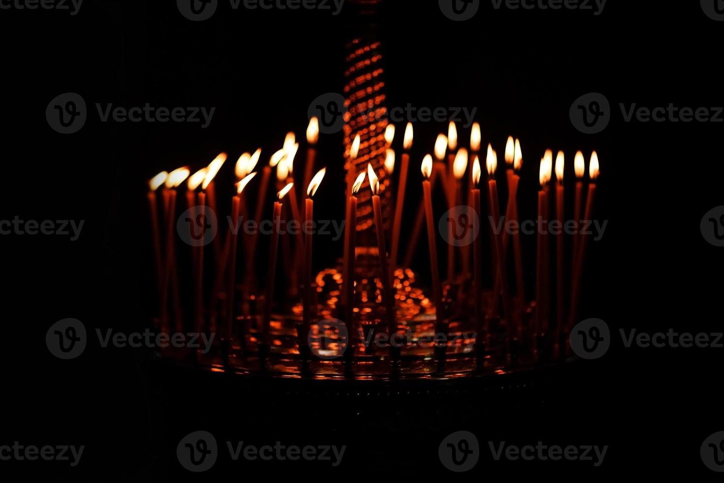 de nombreuses bougies allumées la nuit sur le fond noir à l'église. ensemble de flamme de bougie isolé sur fond noir. groupe de bougies allumées dans l'obscurité photo