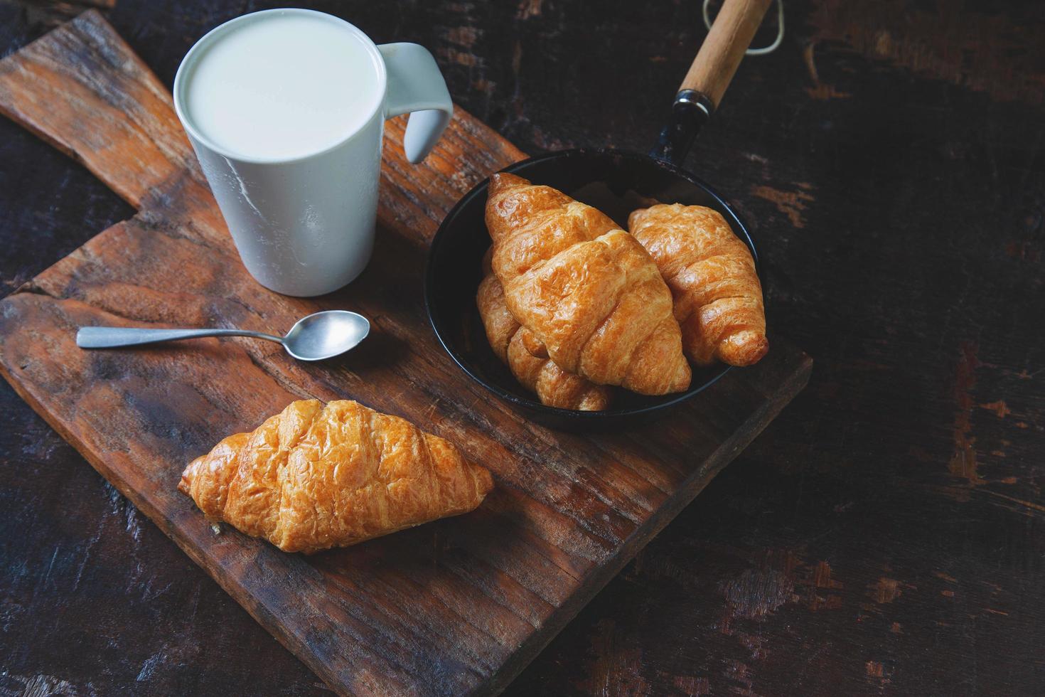 pain de petit-déjeuner, croissants et lait frais sur la table en bois. photo