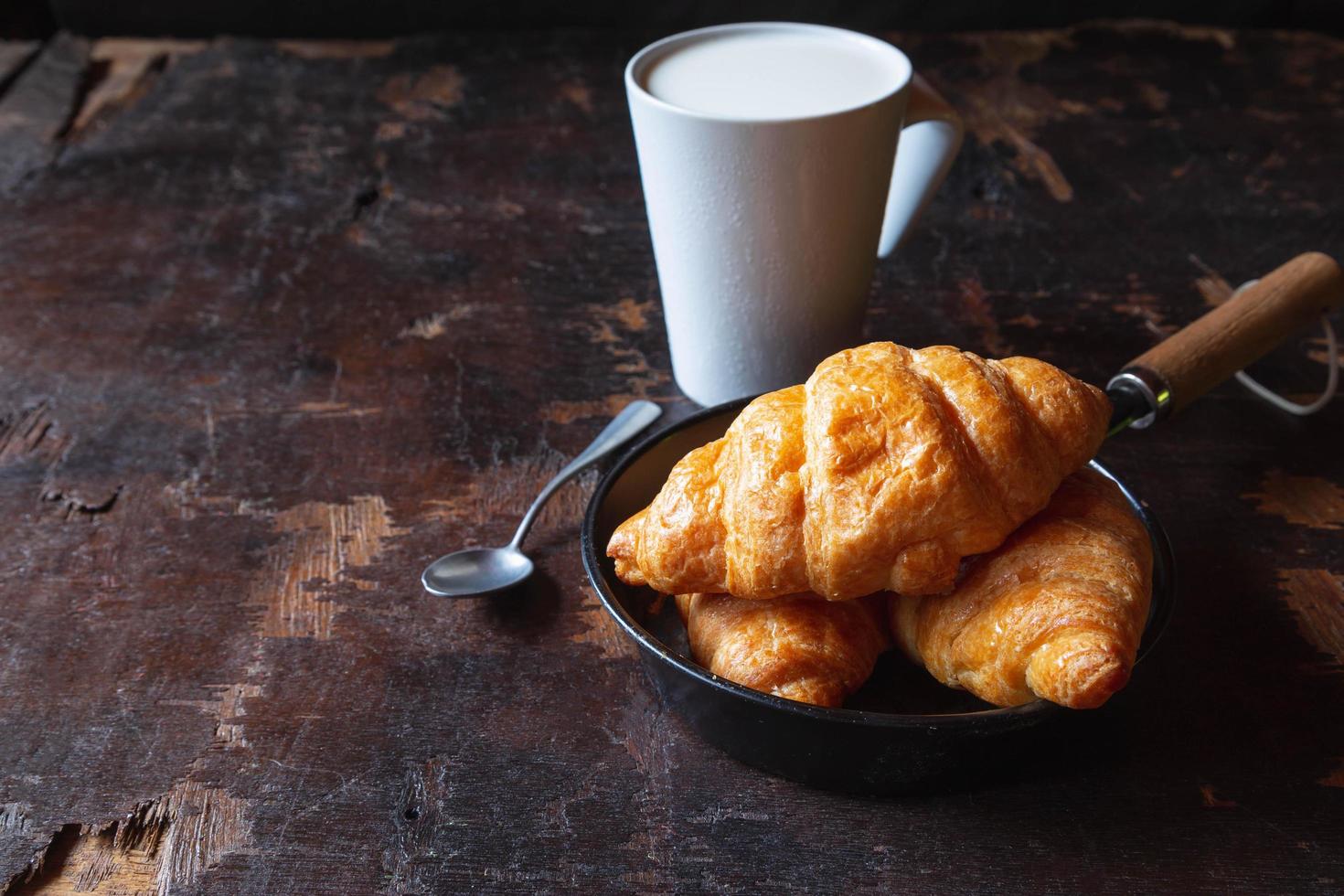 pain de petit-déjeuner, croissants et lait frais sur la table en bois. photo