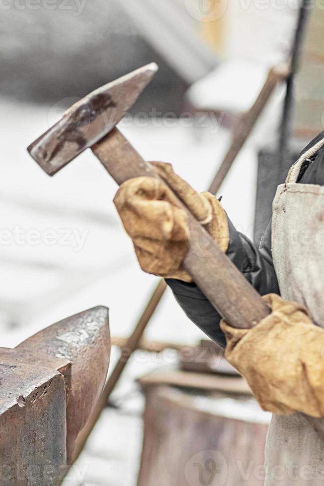 le garçon, le fils du forgeron, se tient à l'enclume. le processus de forge photo