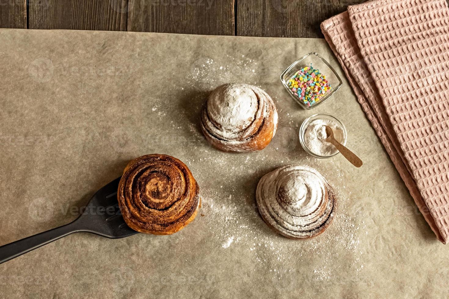 petits pains à la cannelle fraîchement cuits, saupoudrés de sucre en poudre et de garniture de pâtisserie photo