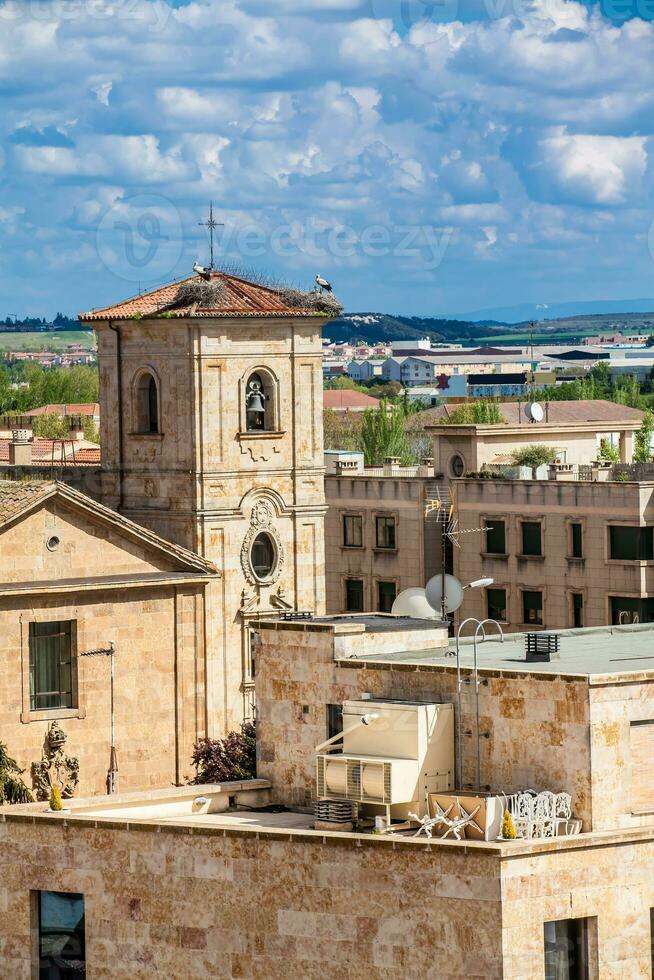 cigognes nidification sur Haut de le cloche la tour de église de Carmen de abajo construit sur le 15e siècle dans le ville de Salamanque dans Espagne photo