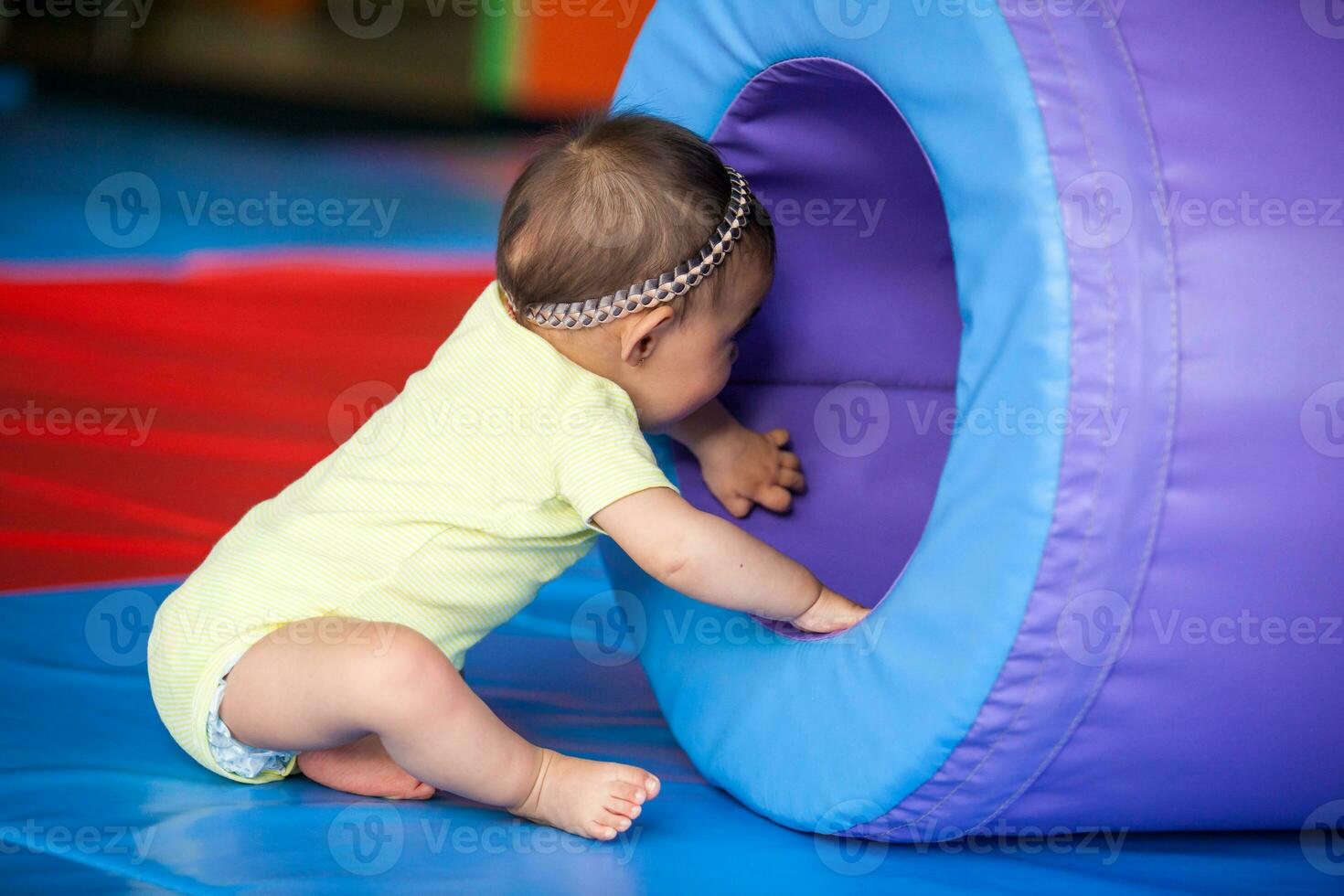 portrait de une content magnifique Dix mois bébé fille en jouant sur une coloré Contexte. de bonne heure stimulation pour les tout-petits concept. photo