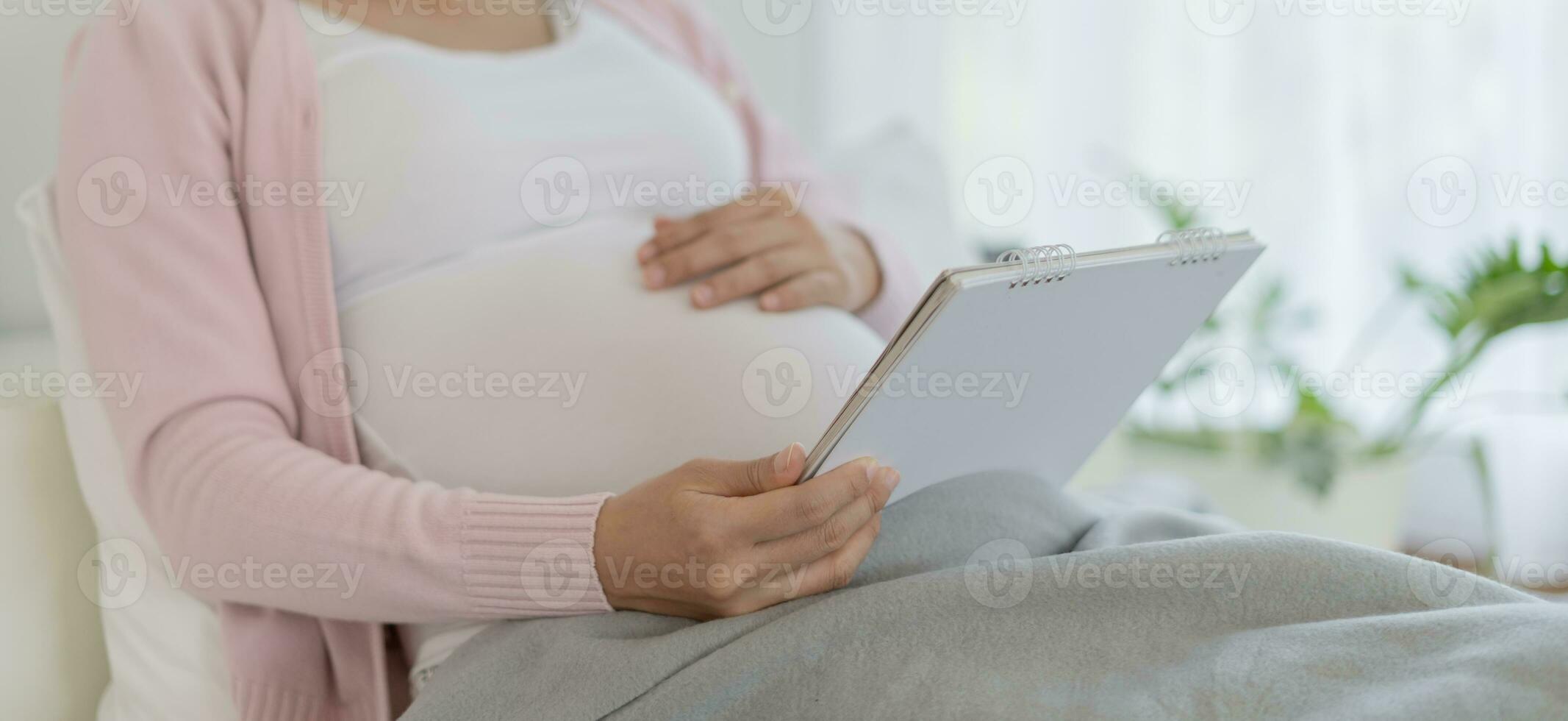 femme enceinte regarde le calendrier pour la date d'accouchement prévue. la césarienne est un moyen pour les femmes enceintes de connaître une date d'accouchement. préparer, nouveau-né, développemental, moniteur, rendez-vous, congé de maternité, âge gestationnel photo