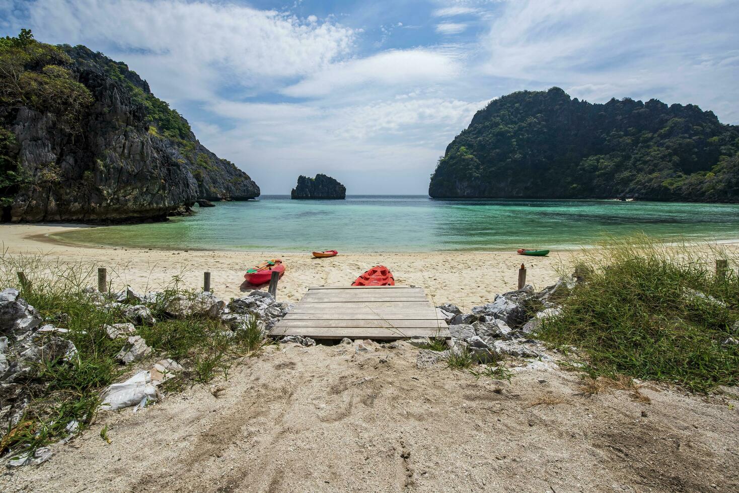 plage sur un île dans myanmar où là sont non gens là sont 4 catak bateaux sur le plage. le l'eau est clair, émeraude vert, une baie avec une petit île dans de face de le baie. photo