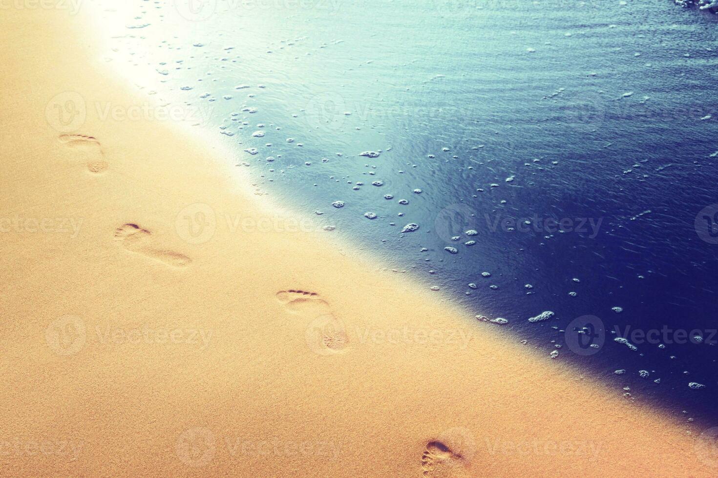 marchant sur la plage, laissant des empreintes de pas dans le sable. photo