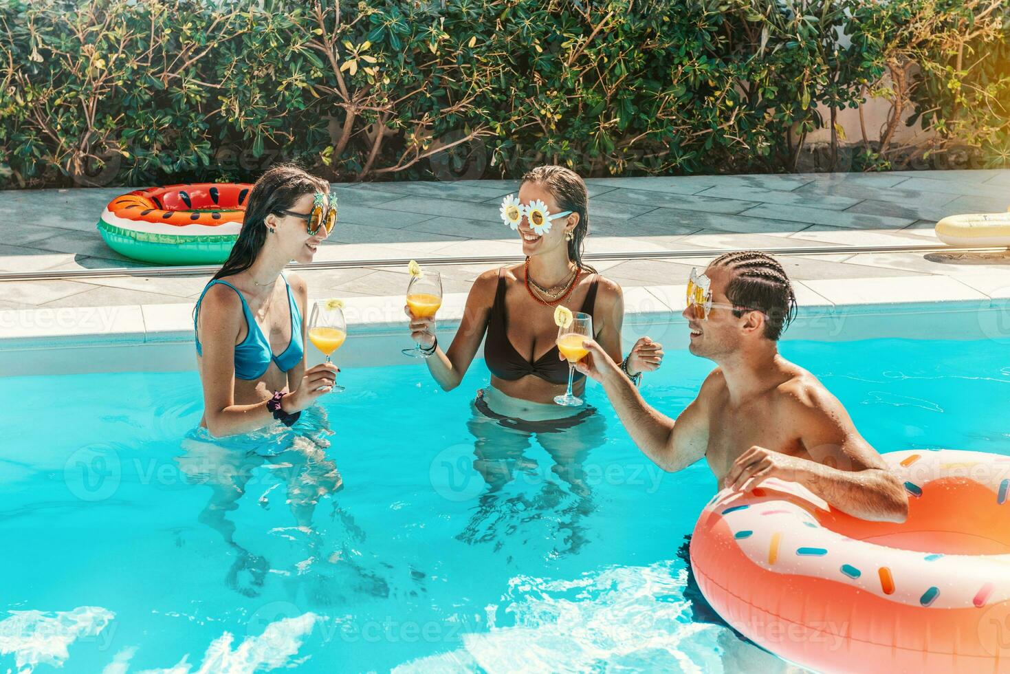 groupe de copains dans maillot de bain boisson une cocktail dans une nager bassin photo