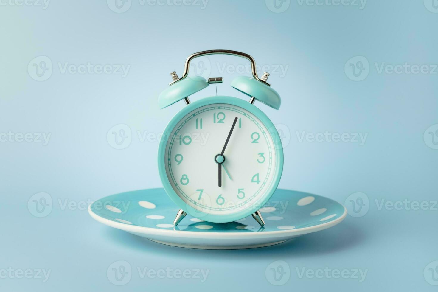 un alarme l'horloge sur un vide assiette contre bleu Contexte photo