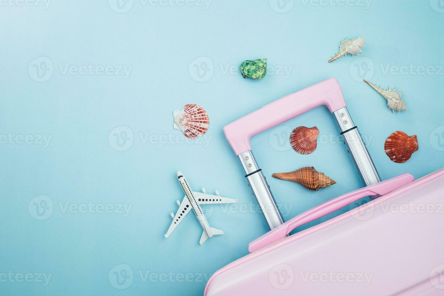 rose bagage avec blanc avion modèle et mer coquilles sur bleu Contexte photo