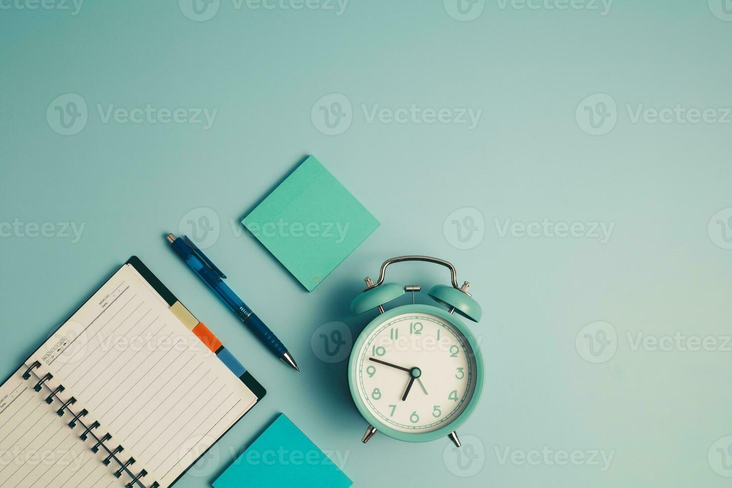 un alarme l'horloge avec une journal intime carnet et autres travail et éducatif matériaux photo