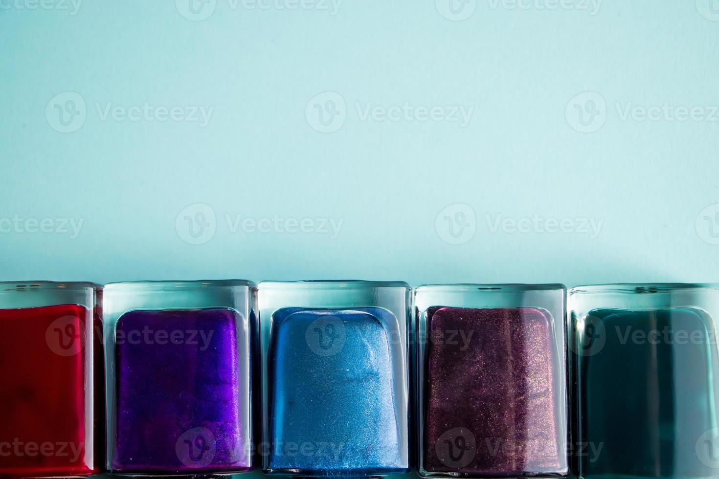 groupe de vernis à ongles de couleur vive sur fond bleu. ensemble de cosmétiques décoratifs pour les soins du corps. photo