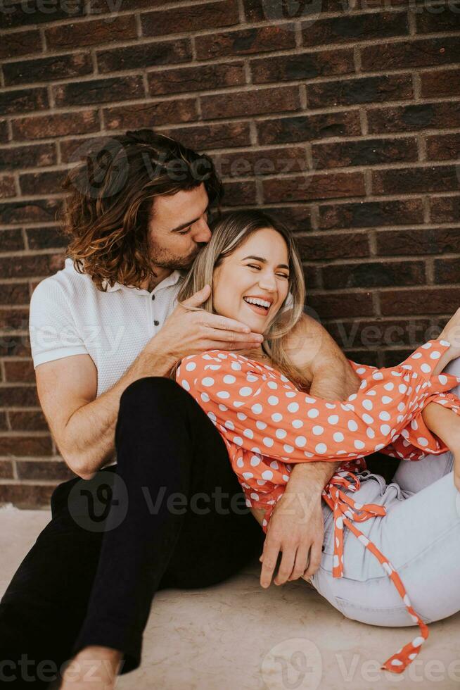 souriant Jeune couple dans l'amour dans de face de maison brique mur photo