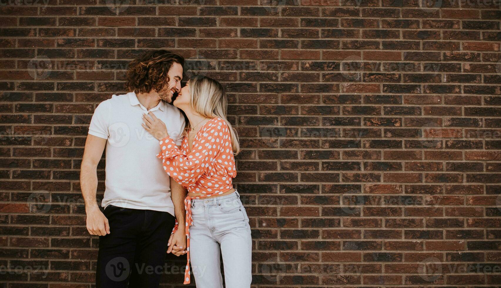 souriant Jeune couple dans l'amour dans de face de maison brique mur photo