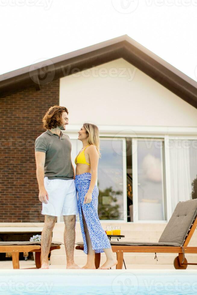 Jeune couple relaxant par le nager bassin dans le maison arrière-cour photo