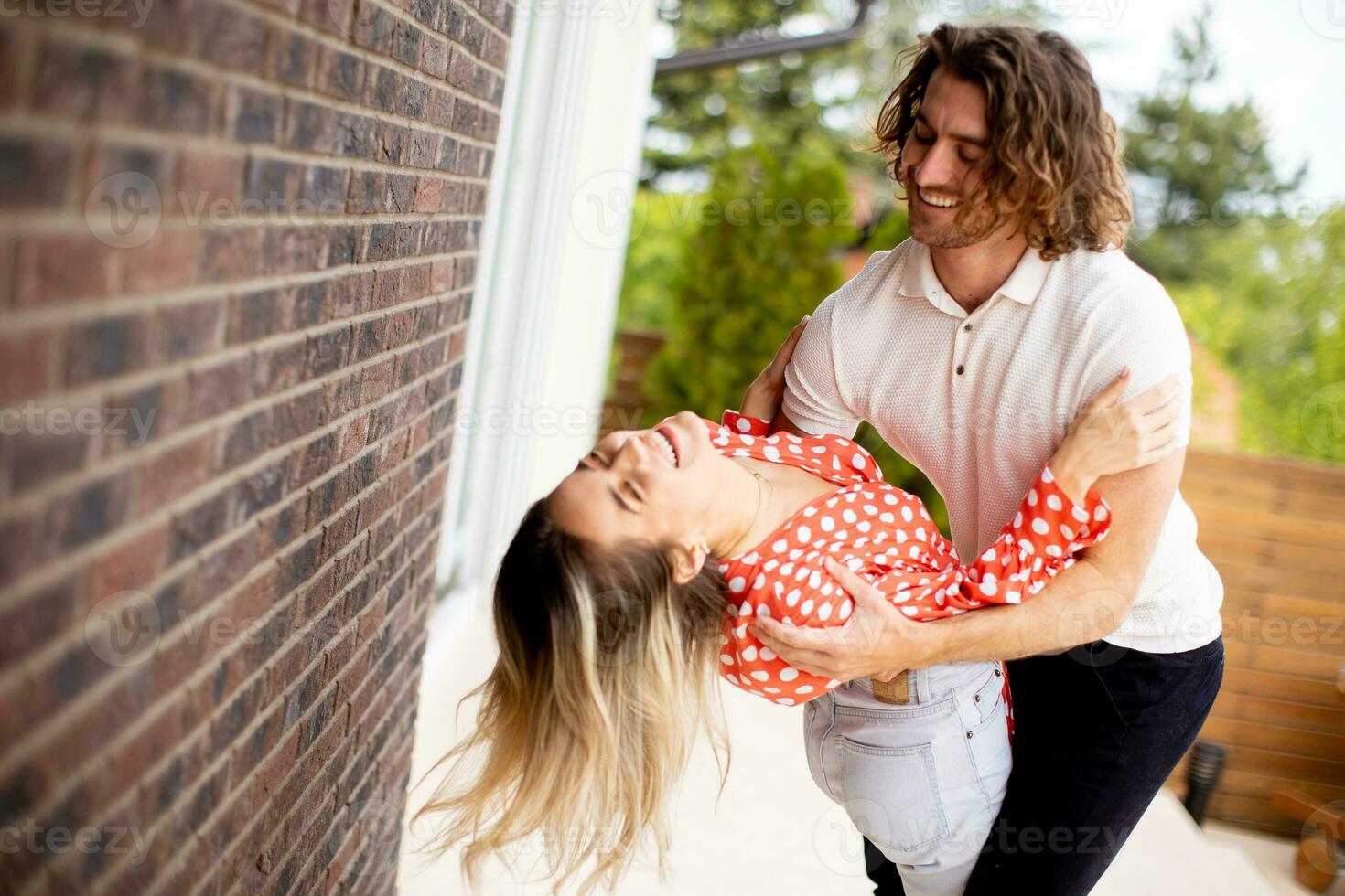 souriant Jeune couple dans l'amour dans de face de maison brique mur photo