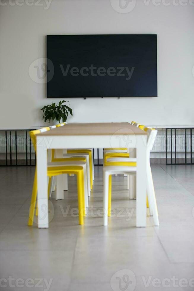 vide Bureau pièce pour réunions et présentations. une table avec Lignes de chaises et une plasma la télé sur le mur. photo