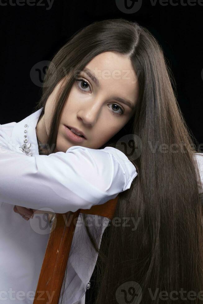 magnifique brunette fille avec longue tout droit cheveux habillé dans une blanc chemise. photo