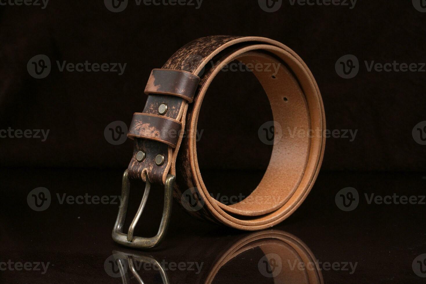 marron cuir ceinture avec éraflures et une métal Boucle sur une foncé Contexte. photo