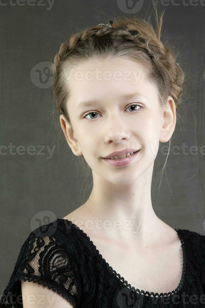 portrait de une magnifique fille adolescent avec une tresser sur une gris Contexte. européen type de affronter. photo