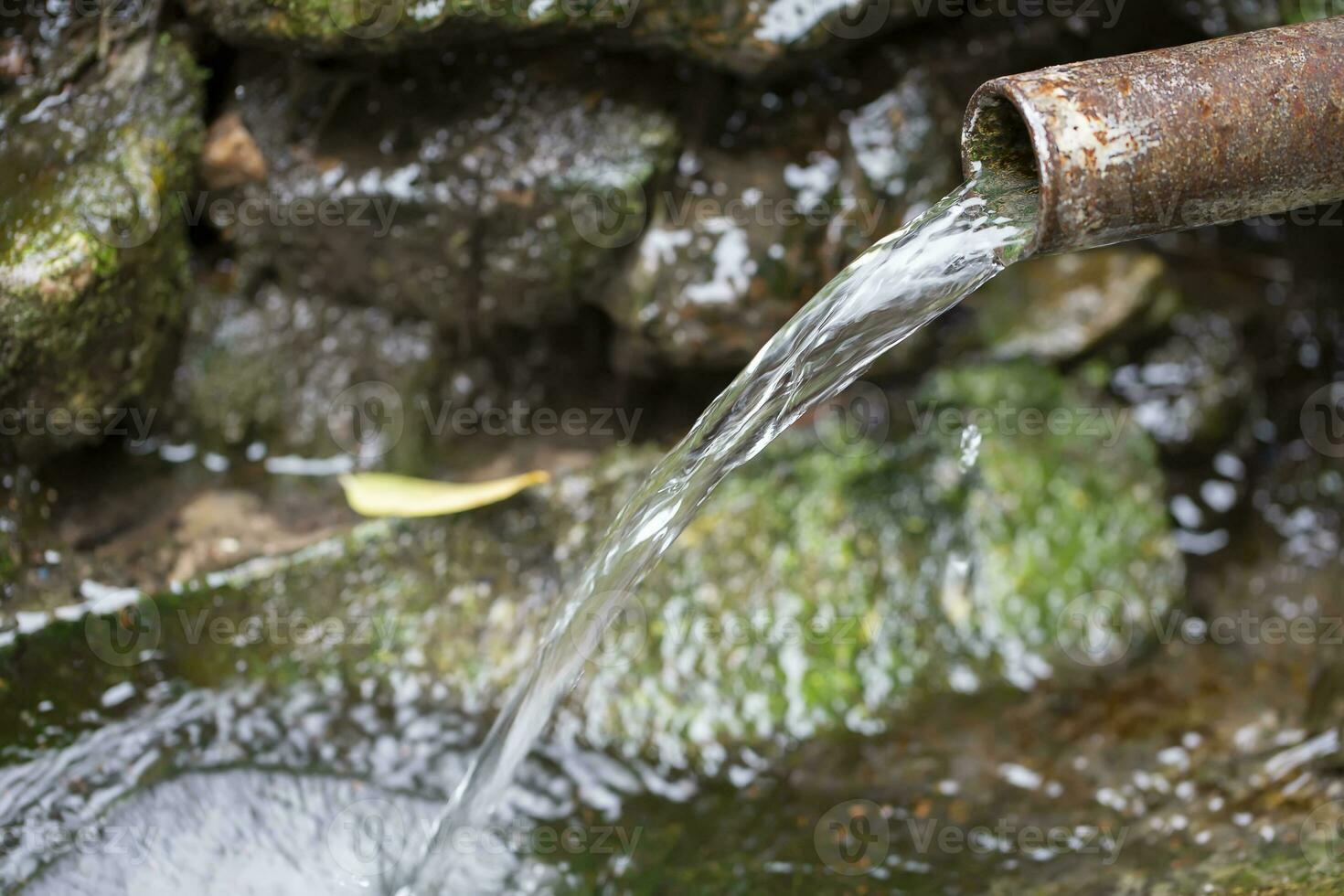 printemps l'eau les flux de une rouillé tuyau. photo